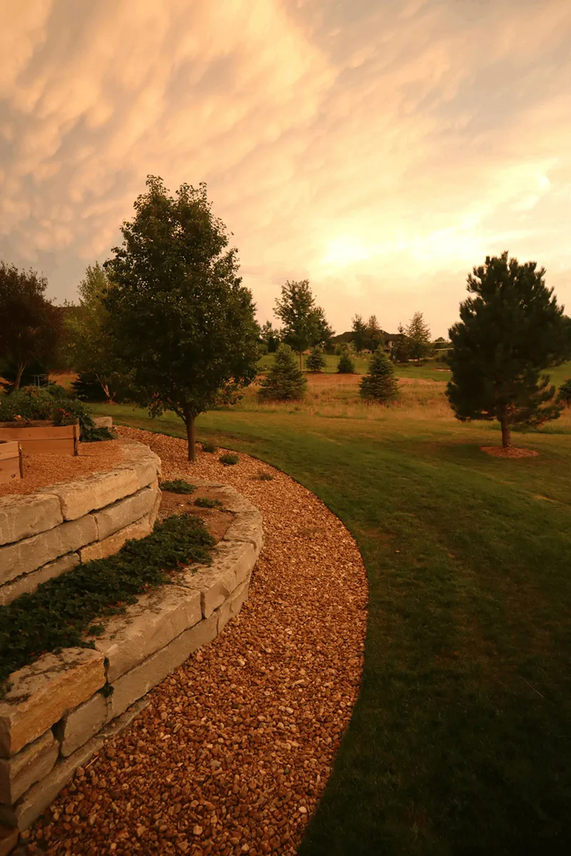 Garten mit Natursteinmauer, Hochbeet und Rasenfläche bei Sonnenuntergang